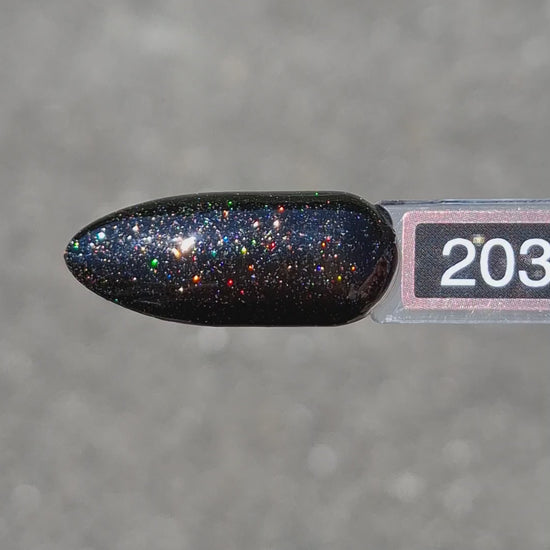 Quida Gelpolish 203 Dusk Fire - diep zwart met multicolor glitter gelpolish aangebracht op nagels in het zonlicht, 15ml