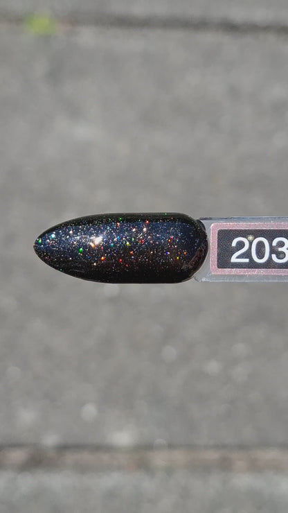 Quida Gelpolish 203 Dusk Fire - diep zwart met multicolor glitter gelpolish aangebracht op nagels in het zonlicht, 15ml